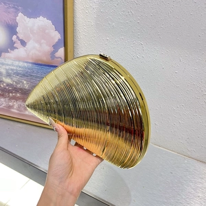 Close-up of golden shell evening clutch with metallic wavy texture and hard shell design