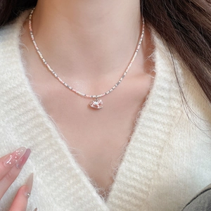 Détail d'un collier de perles avec pendentif cheval rose porté par un mannequin