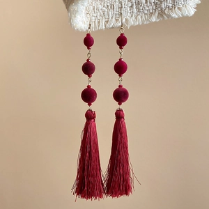 Close-up of elegant burgundy velvet beaded tassel earrings with gold-tone hooks
