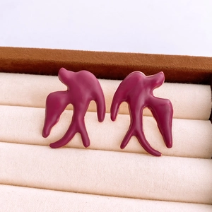 Detailed macro view of purple swallow stud earrings in a beige velvet jewelry box
