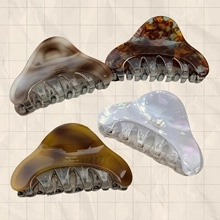 Detail of four matte flower hair clips in tortoiseshell and cream finishes on a beige paper