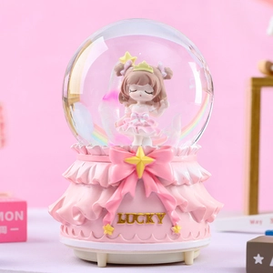 Detail of pink crystal ball music box with lucky lettering and girl figurine inside