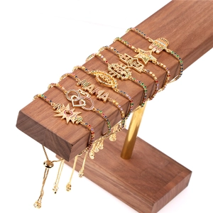 Adjustable gold bracelets with colorful zircons and MAMA charms on a wooden display stand