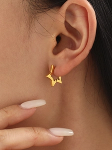 Close-up of gold star-shaped stainless steel huggie hoop earrings on a model