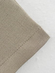 Detail of beige cotton linen fabric showing high-quality woven texture and stitching