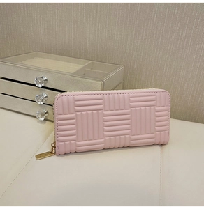Close-up of pink long wallet featuring geometric embossed texture and zip-around closure