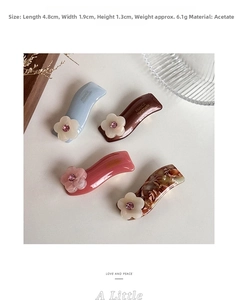 Detail of four acetate hair clips with rhinestone flowers and elegant gold logo accents