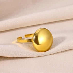 Detail of a minimalist gold dome ring with polished metal finish on soft fabric background