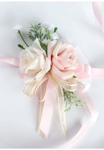 Dettagli di rose finte crema e rosa su un corpetto da polso nuziale con nastri di seta