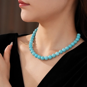 Close-up of minimalist turquoise beaded necklace on neck with polished blue round stones