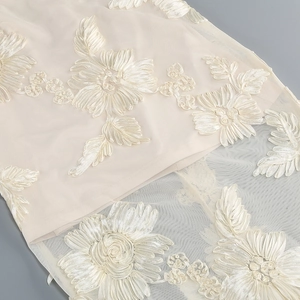 Detailed view of champagne floral ribbon embroidery on lightweight tulle mesh fabric
