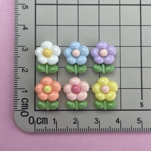 Detailed size view of colorful resin mini flower charms on a centimeter scale mat