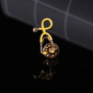 Detail of yellow enamel stethoscope brooch with gold-tone plating on reflective black base
