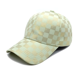 Detail of light green baseball cap with gold checkered pattern and woven fabric texture