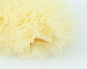 Dettaglio macro degli strati di tulle increspato su un top senza maniche giallo chiaro
