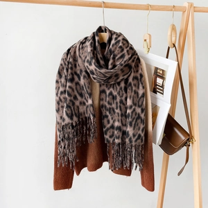Close-up of brown leopard print scarf with soft fringe tassels on a wooden hanger