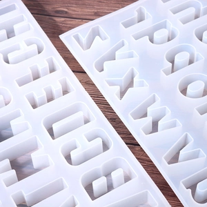 Macro shot of translucent silicone alphabet molds for resin casting on wooden background