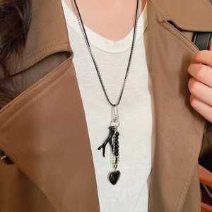 Close-up of double-layer necklace with black heart pendant and coral-like branch charm