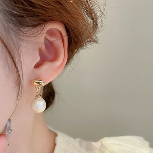 Close-up of model wearing vintage cotton pearl earrings with golden geometric details