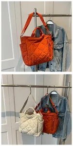 Detail of diamond-quilted tote bag featuring side pockets and adjustable nylon strap