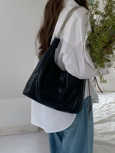 Macro detail of soft black leather tote bag with thick silver metal chain shoulder strap