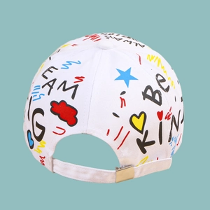 Détail de la boucle en métal argenté et des motifs graffiti colorés sur la casquette en coton blanc