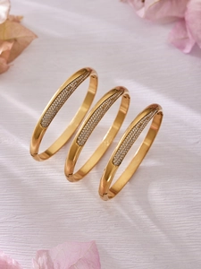 Gros plan de bracelets en acier doré à charnière avec micro-pavage de zircons cubiques
