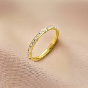 Macro detail of a gold titanium steel ring featuring a sparkling single row of crystals
