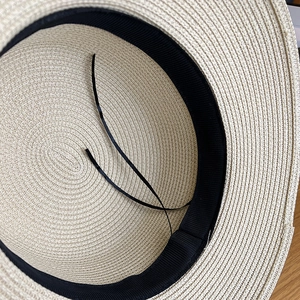 Detail view of woven straw hat interior featuring black sweatband and adjustable drawstring