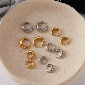 Boucles d'oreilles créoles en acier inoxydable or et argent sur plateau en céramique