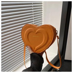Detail of orange heart-shaped crossbody bag with embossed texture and fashion text