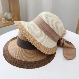 Detail of summer straw hats with elegant wavy brims and premium ribbon bow decoration