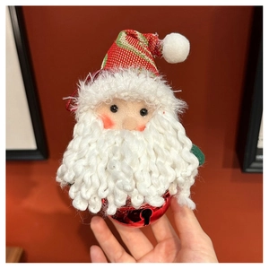 Detail of handmade Santa plush ornament with a red metal bell and knitted hat decor