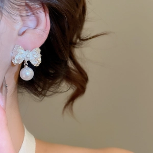 Gros plan de boucles d'oreilles nœud argenté avec texture plissée et perle sur le mannequin