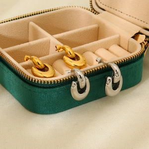 Macro view of interlocking geometric gold and silver earrings on green velvet jewelry box