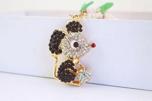 Detailed close-up of golden mouse pendant with sparkling black and clear rhinestones