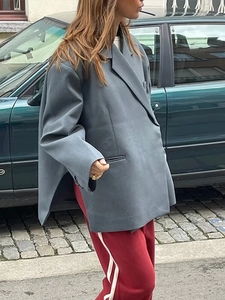 Outdoor street style shot of the side slit detail on a grey oversized blazer jacket