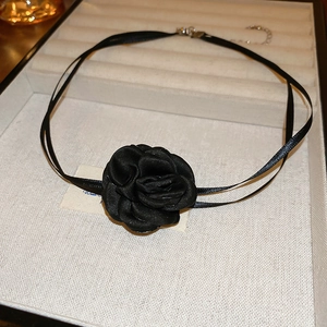 Gros plan du collier choker rose en tissu noir avec pétales satinés et chaîne réglable