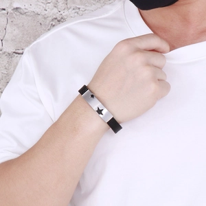 Detail shot of black silicone bracelet with silver star-engraved stainless steel plate