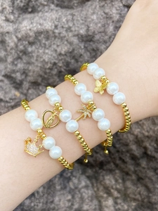 Detail of four-piece layered bracelet set with gold beads, pearls and thematic charms