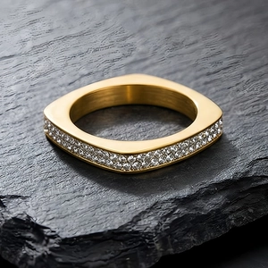 Détails d'une bague dorée en acier inoxydable sertie de zircons sur fond minéral sombre