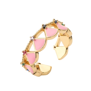 Macro shot of gold shell ring with pink enamel triangles and colorful gemstones