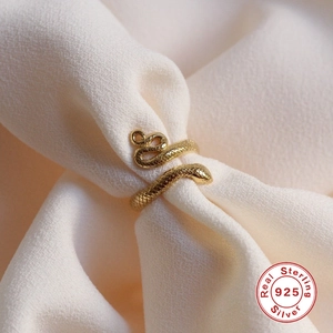 Macro shot of 925 sterling silver snake ring with golden finish on textured fabric