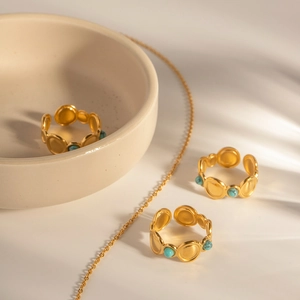 Golden turquoise open ring with geometric circular design on a ceramic display