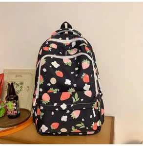 Detail of cute strawberry and cloud patterns on a durable black student backpack