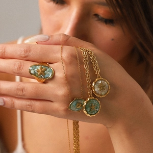 Detail of golden starfish necklace and ring set with white and green shell inlay