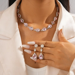Gros plan sur l'ensemble collier et boucles d'oreilles argent avec cristal rose goutte