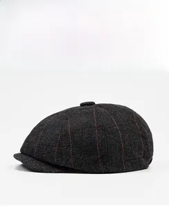 Side view detail of a dark grey herringbone newsboy cap with red windowpane check pattern