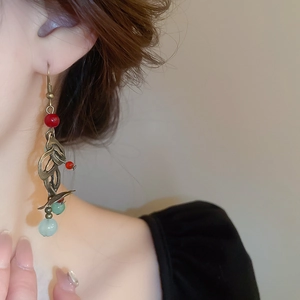 Détail de boucles d'oreilles ethniques avec perles rouges et finition métal rétro
