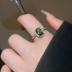 Detail of 18k gold-plated halo ring with green tiger eye stone worn on a finger